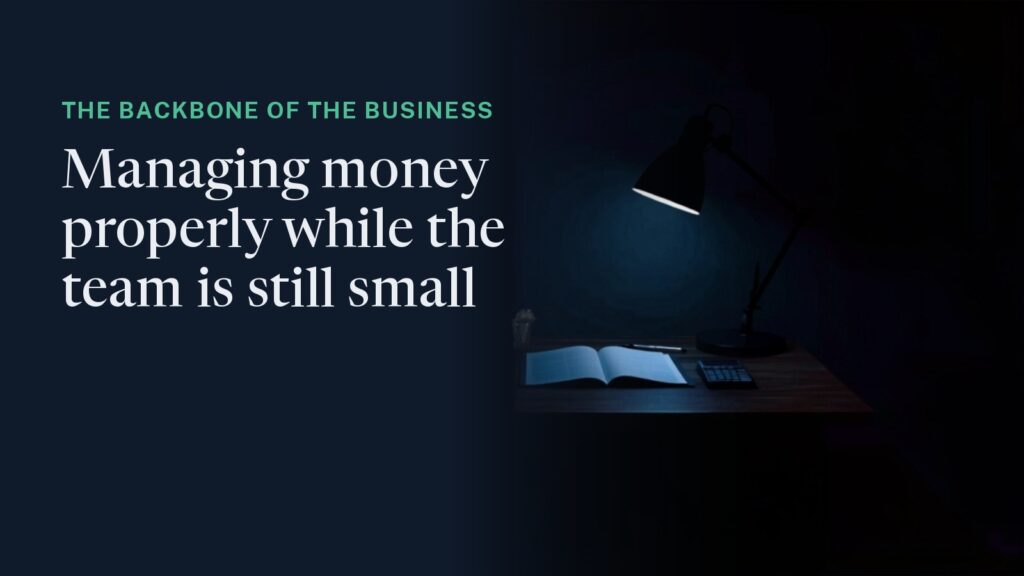 Cover: a small desk at night under a single lamp, an open ledger and a calculator, the room dark around it. Overlaid: "The backbone of the business - managing money properly while the team is still small."