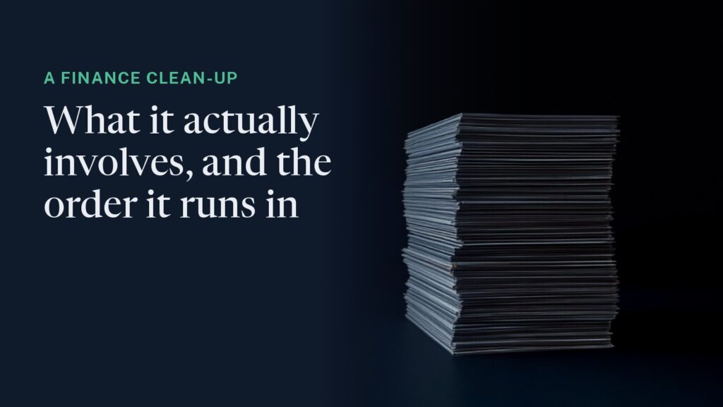 Cover: a tall stack of bank statements lit from above against deep navy, one index tab picked out in green. Overlaid: "A finance clean-up - what it actually involves, and the order it runs in."